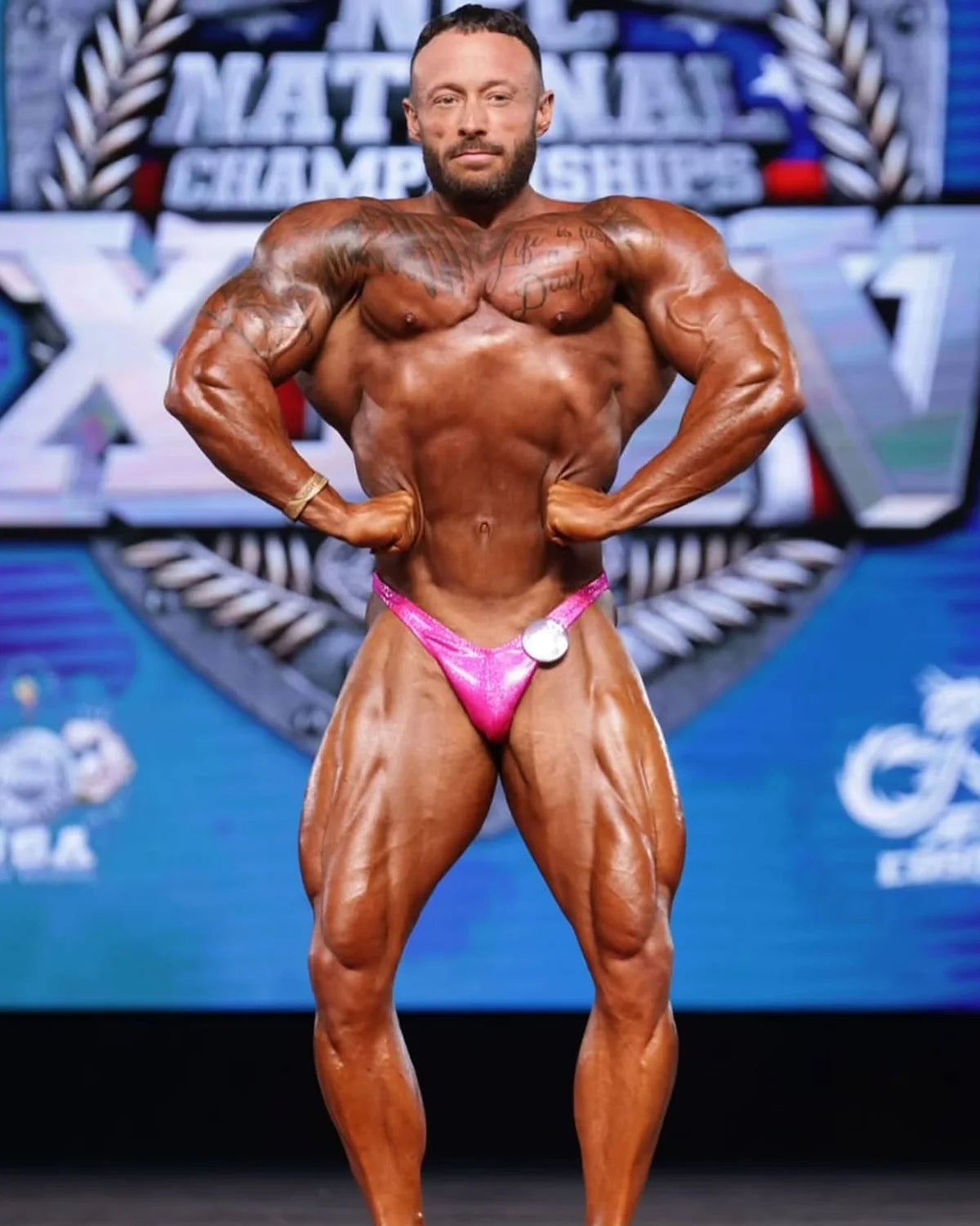 Custom bodybuilding trunks in hot pink shatterglass hologram, Rio cut with gather, front view NPC and IFBB stage-legal