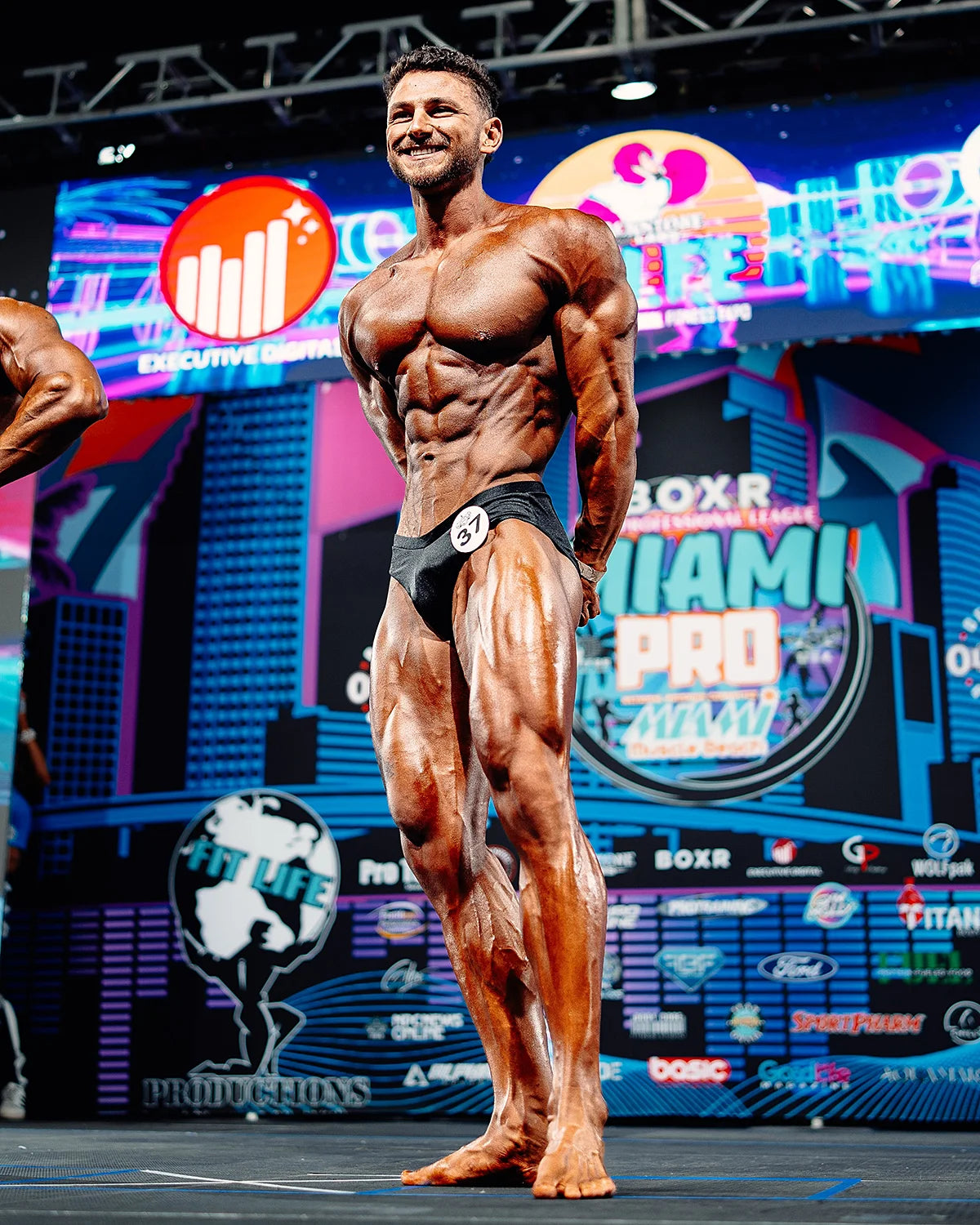 Matte lycra classic physique trunks worn on stage by NPC classic physique competitor, front pose showing regular cut traditional silhouette